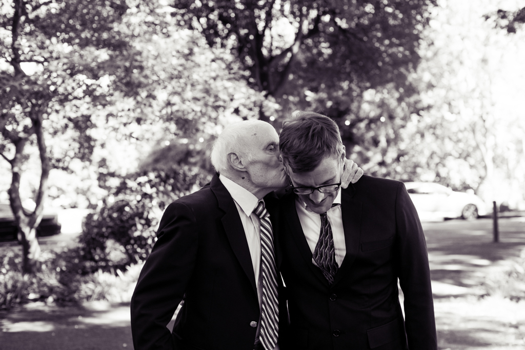 grandpa gives the groom a kiss on his head