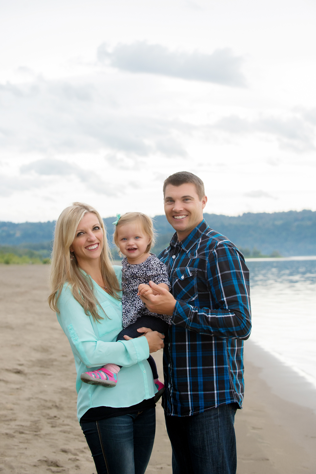 a mom and dad hold a baby girl at cottonwood beach