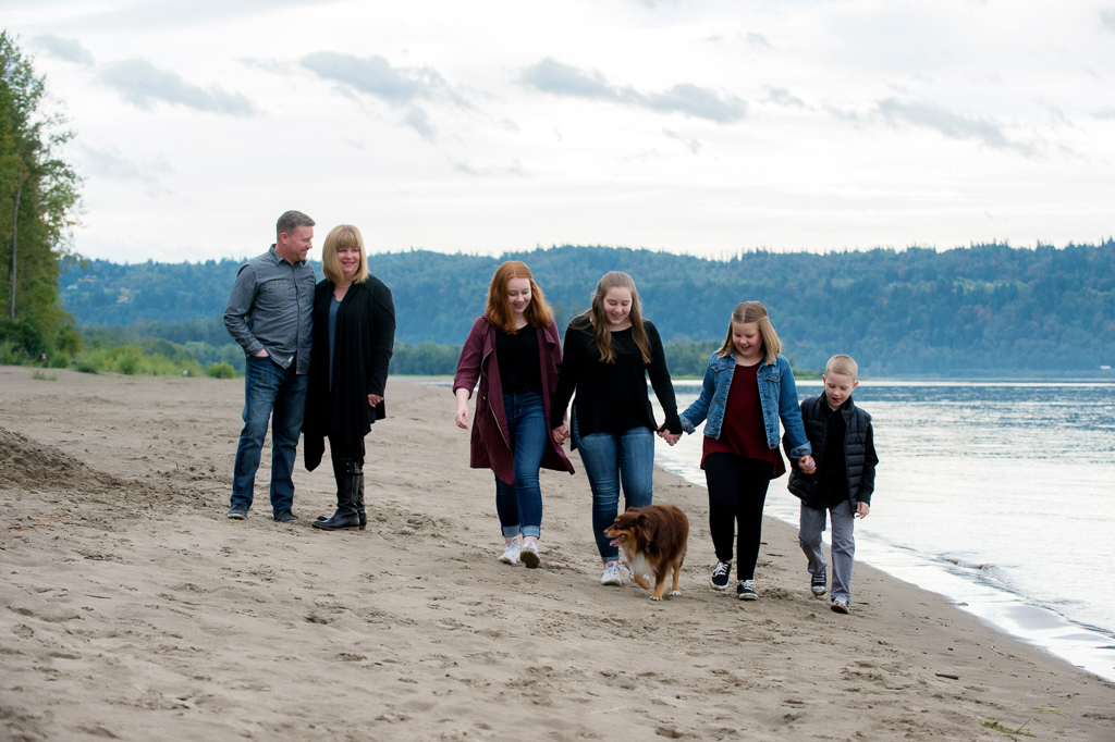 a family of 6 walk along cottonwood beach with their dog