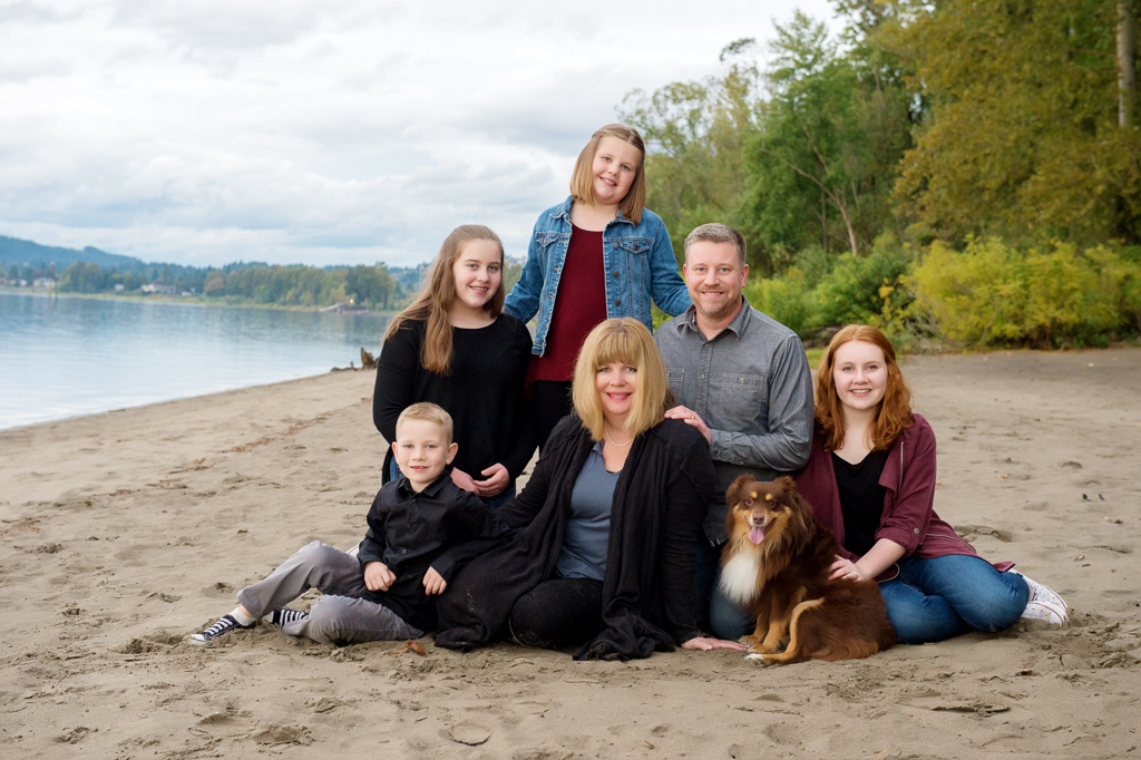 a family of 6 sit on the sand at cottonwood beach next to the columbia river with their dog