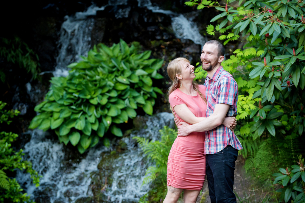 a couple laugh in front of a waterfall