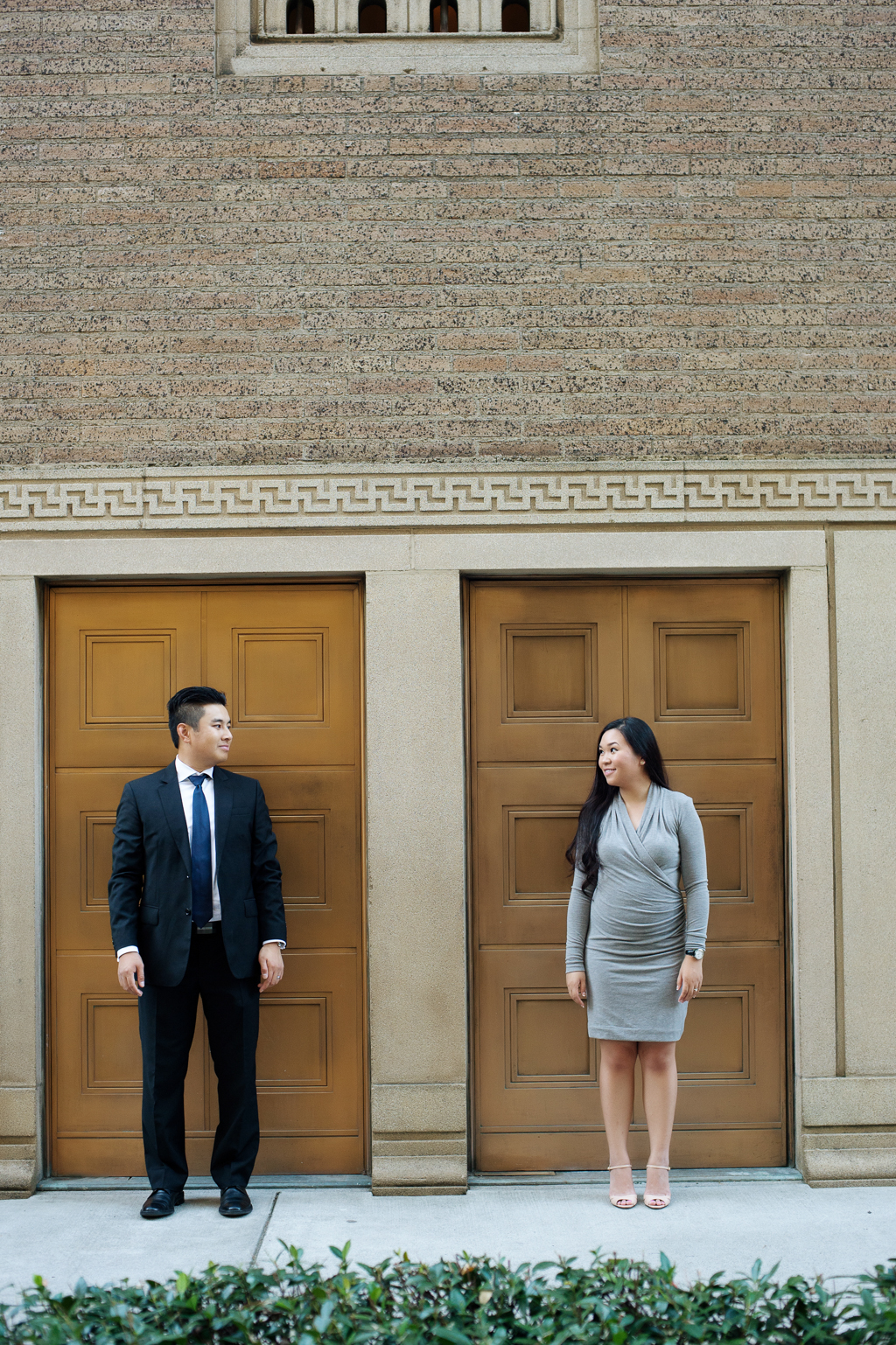 a man and woman stand in front of gold doors in front of the portland art museum and look at each other
