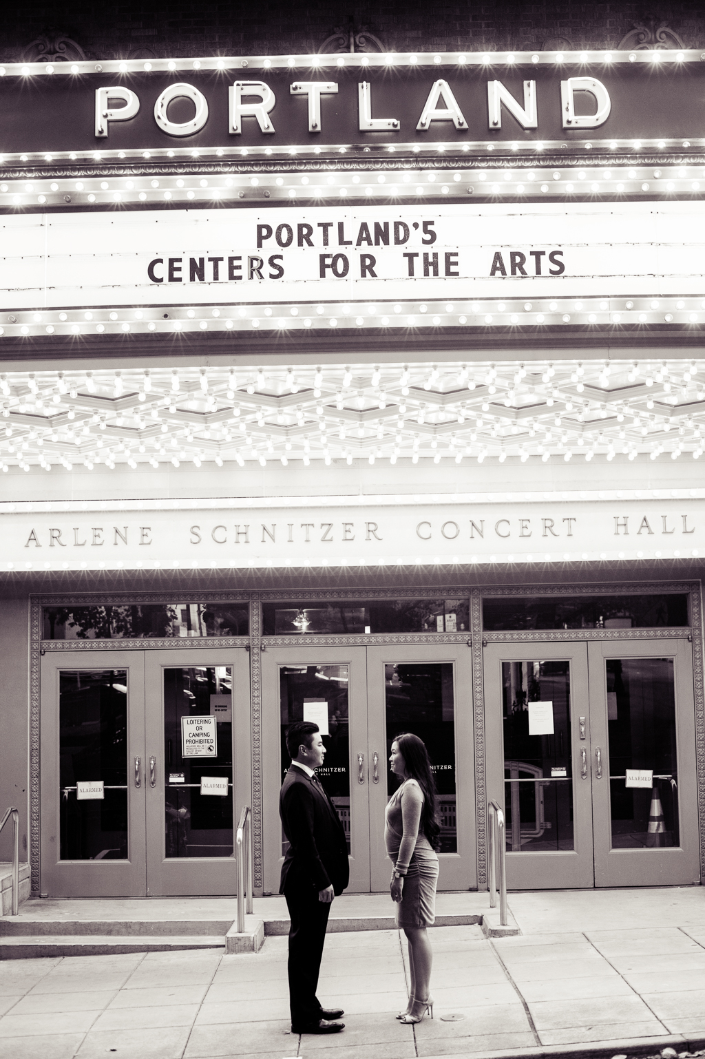 a couple stand under the portland theater marquee facing each other