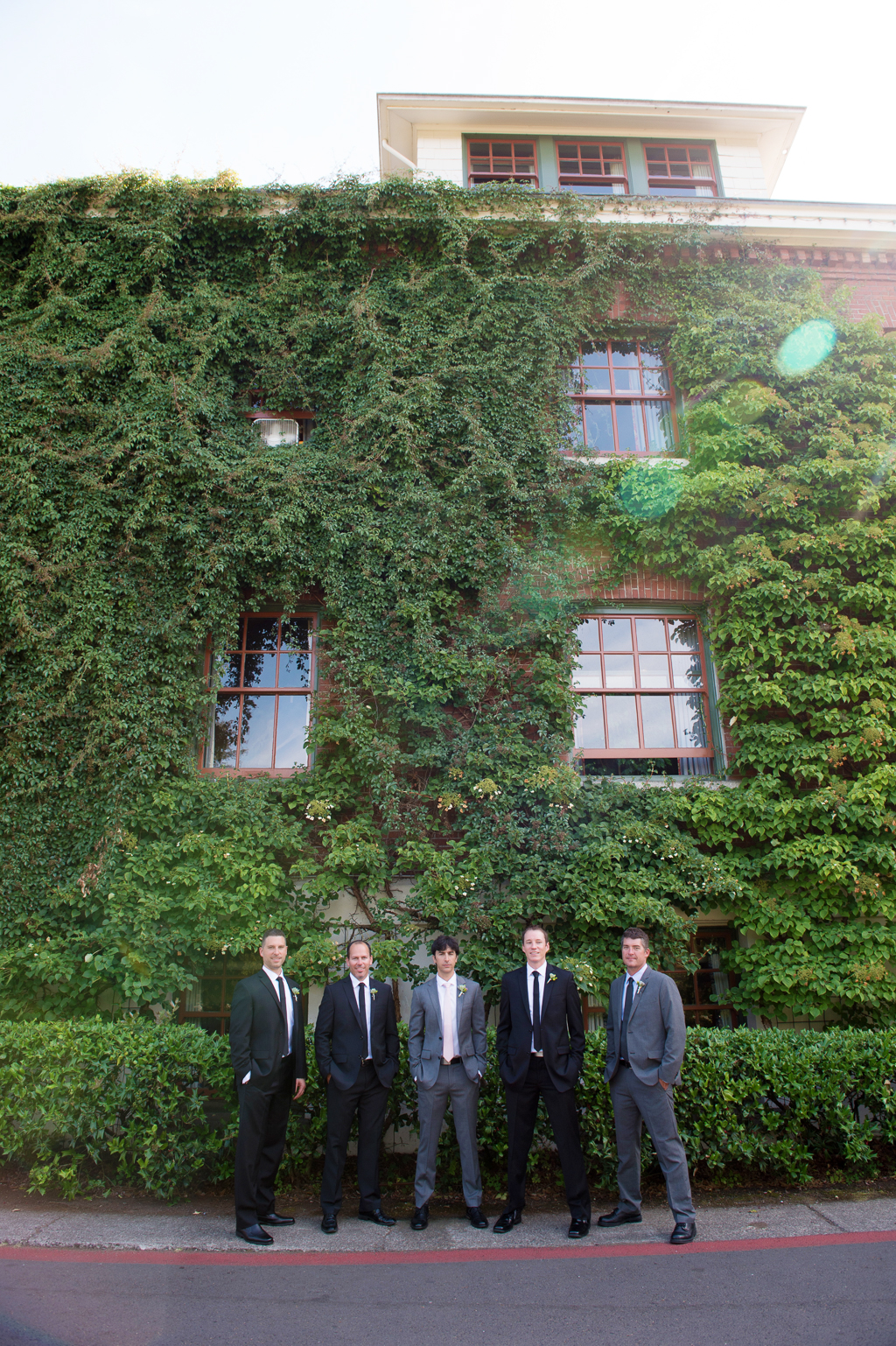 groomsmen stand under ivy covered wall at edgefield