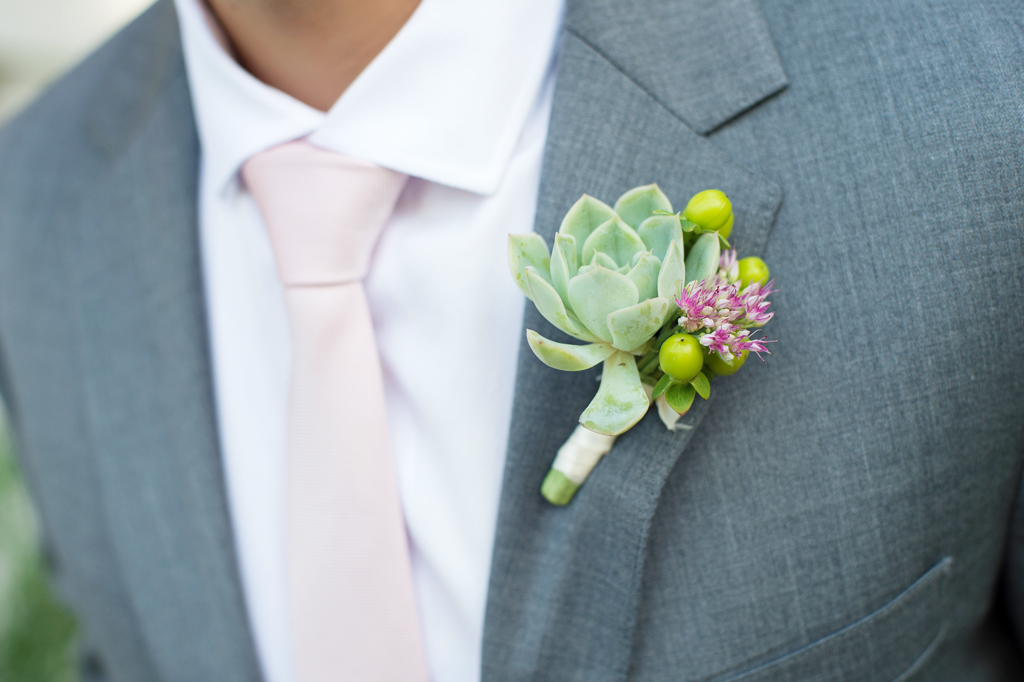a groom wears a succulent boutonniere