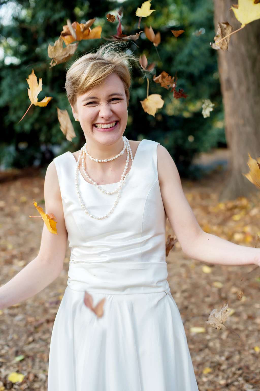 girl in a white dress and pearls  throws leaves into the air
