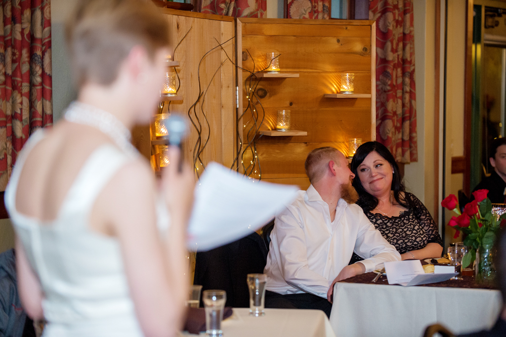 bride and groom look at each other lovingly as sister reads toast