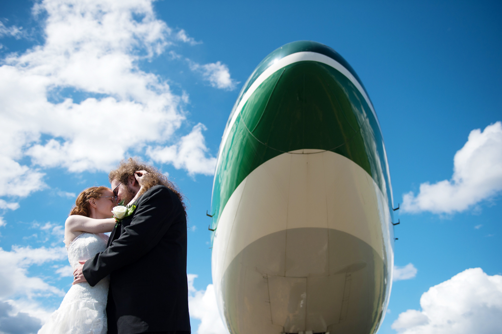 bride and groom under a giant airplane