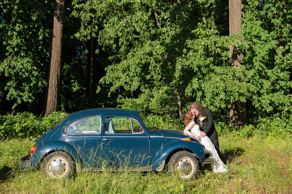 bride and groom lean on a blue vw bug