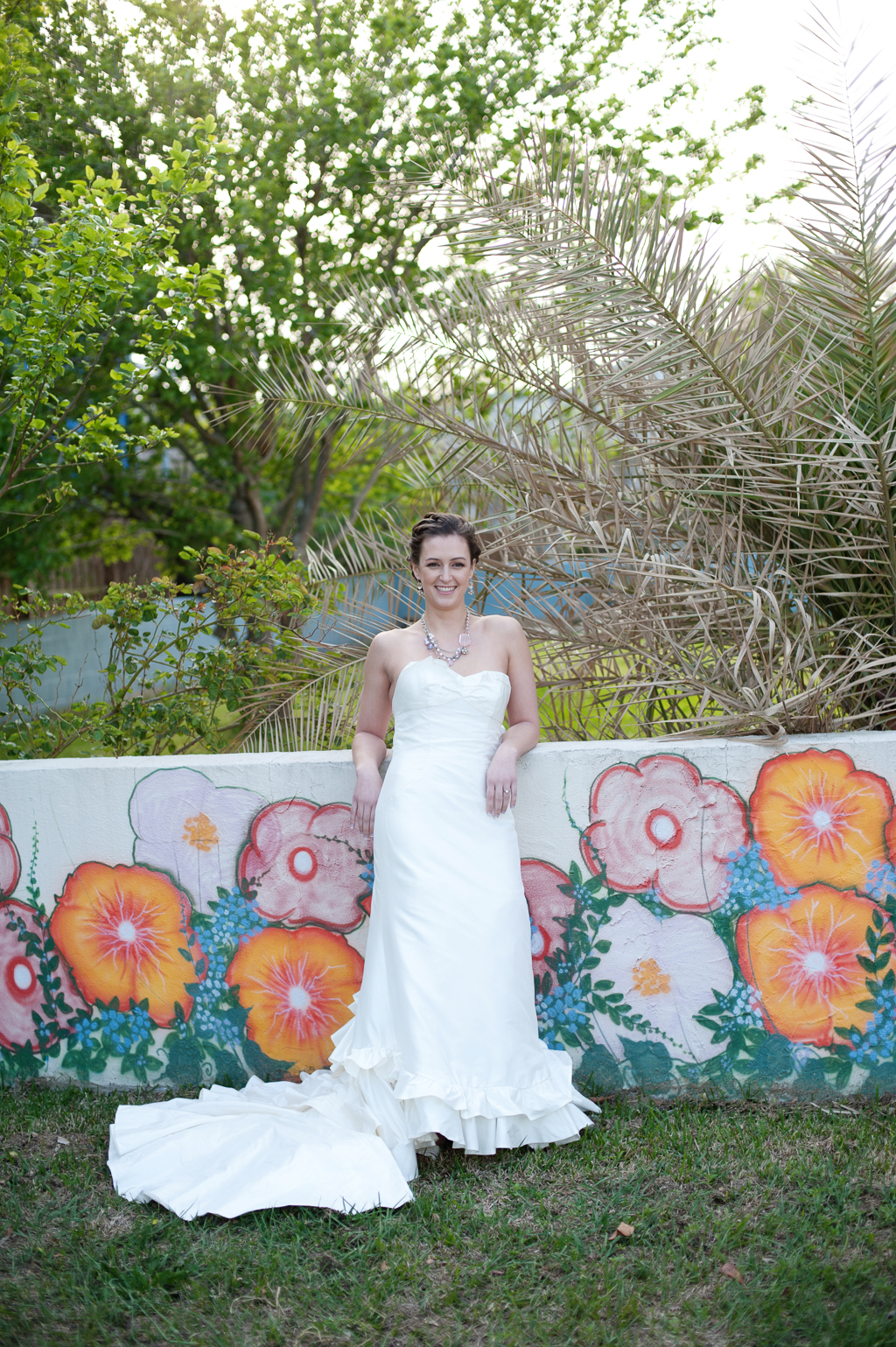 bride leans against wall with colorful flower mural