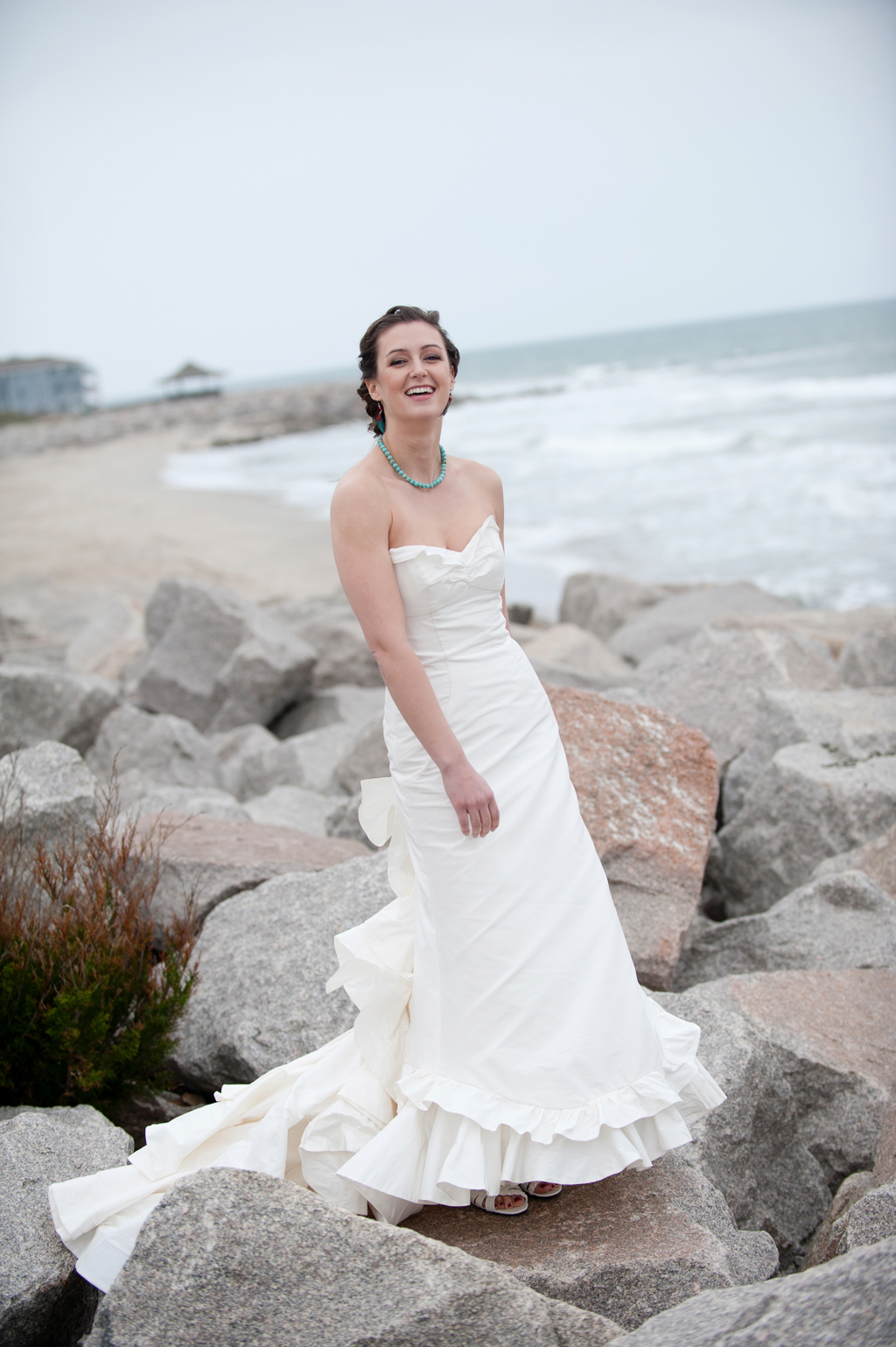 bride laughs and stands on rocks at fort fisher