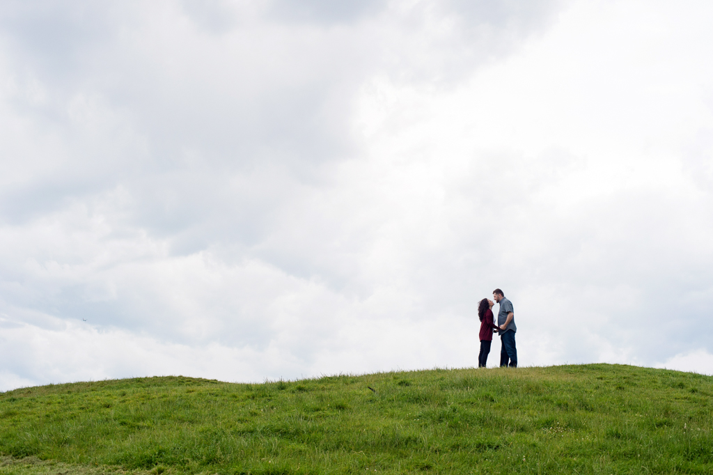 a couple kiss standing on the horizon of a hill at gas works park