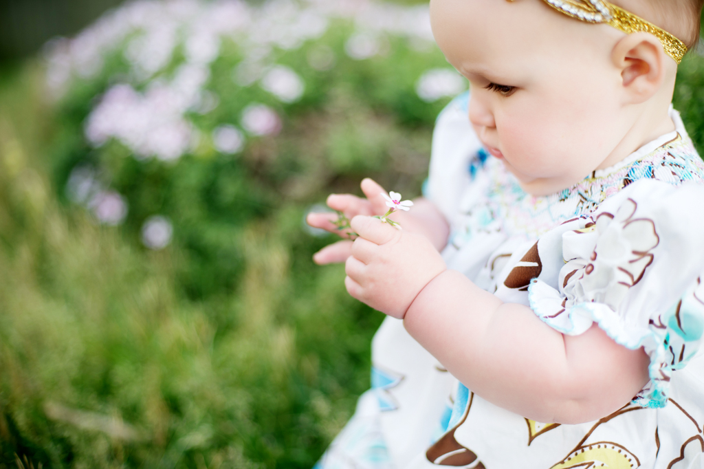 baby girl plays with small white flower