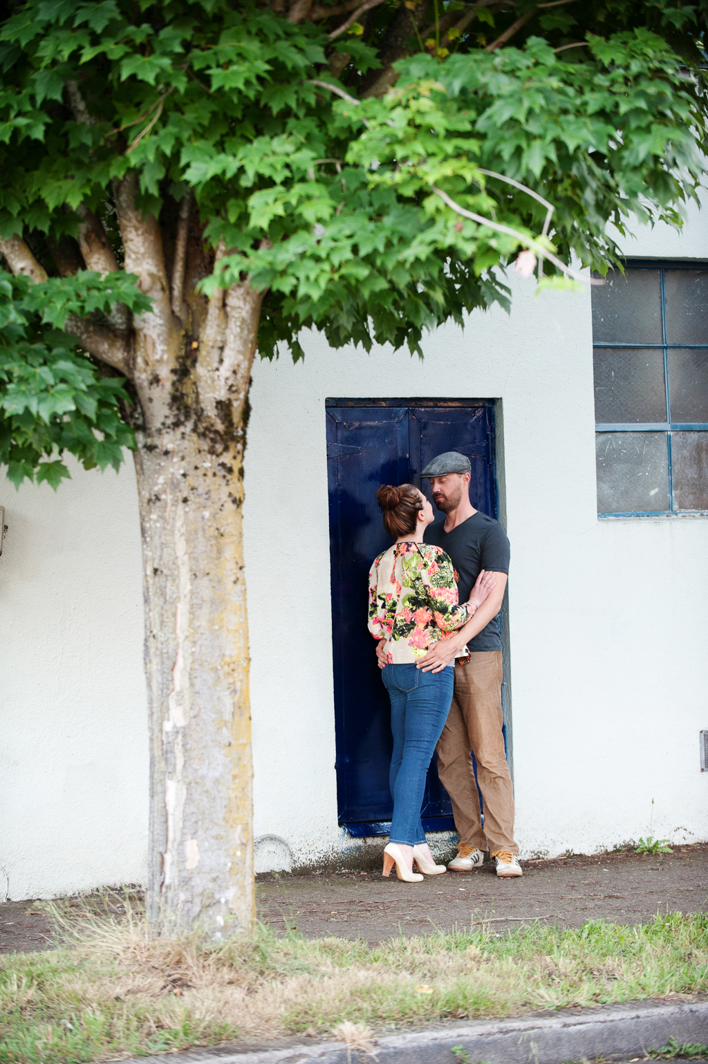a couple stand in doorway with a blue door framed by a tree