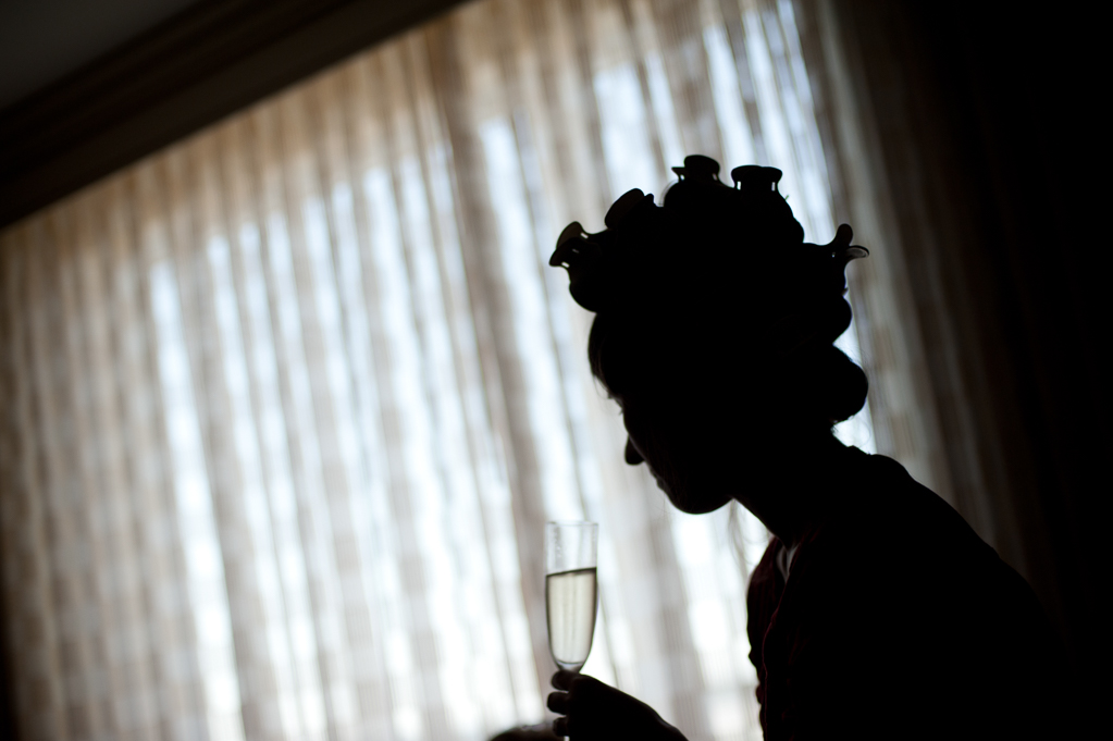 silhouette of girl in hair curlers with glass of champagne