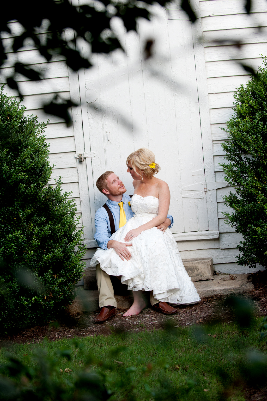 a bride and groom sit on a stoop in front of a white building