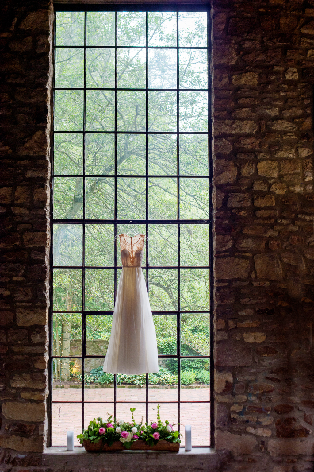 wedding dress hangs from giant window