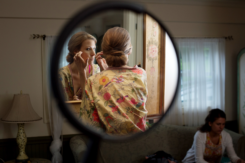 bride gets ready for wedding in a round mirror