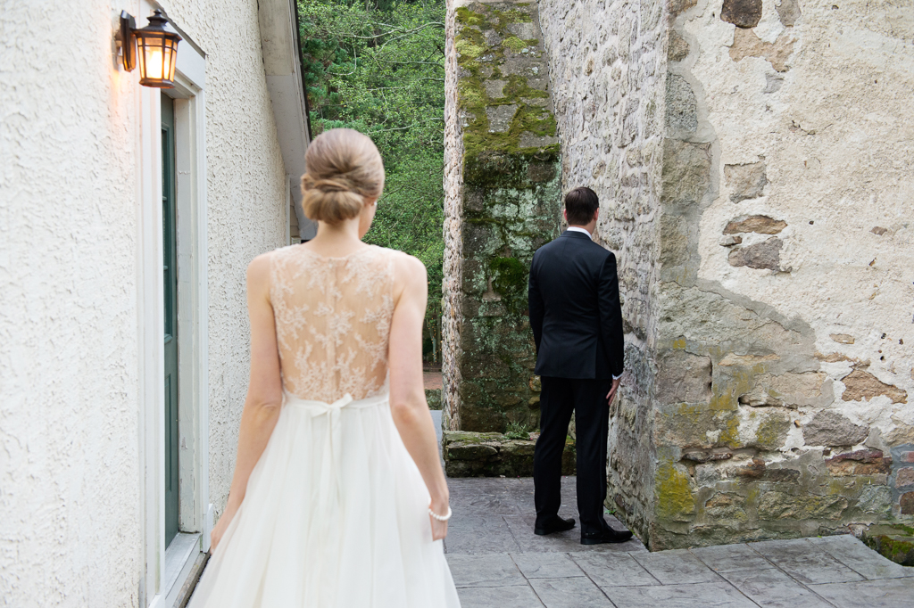 bride sneaks up behind groom as he waits for her in corner of holly hedge estate