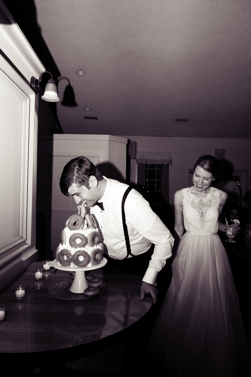 groom eats a donut directly off the top of his groom's cake on his wedding day