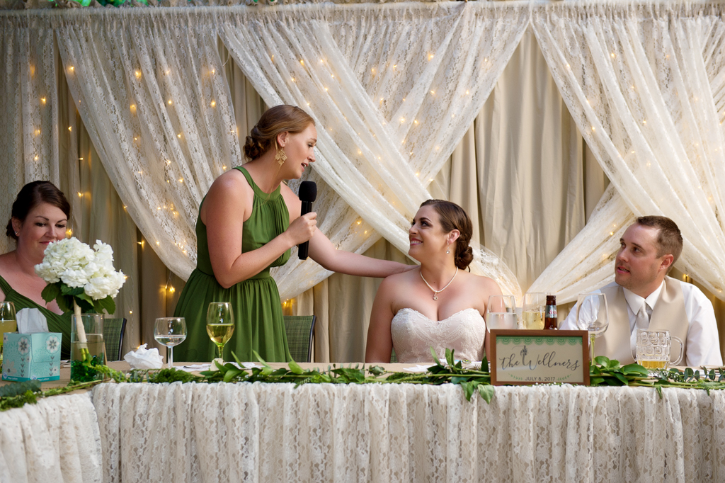 maid of honor touches brides shoulder during the reception toasts
