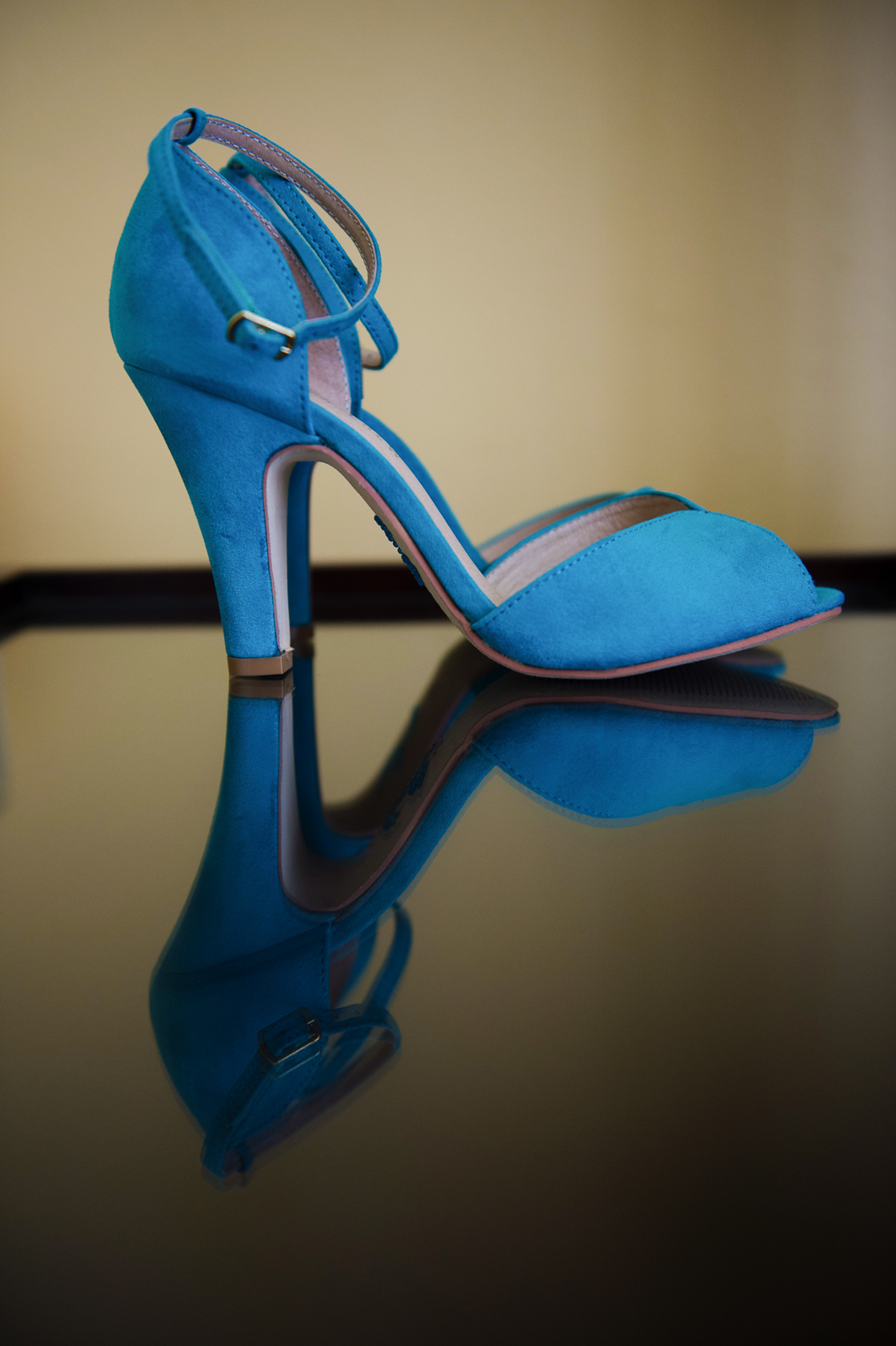 turquoise high heeled wedding shoes reflect on a shiny surface