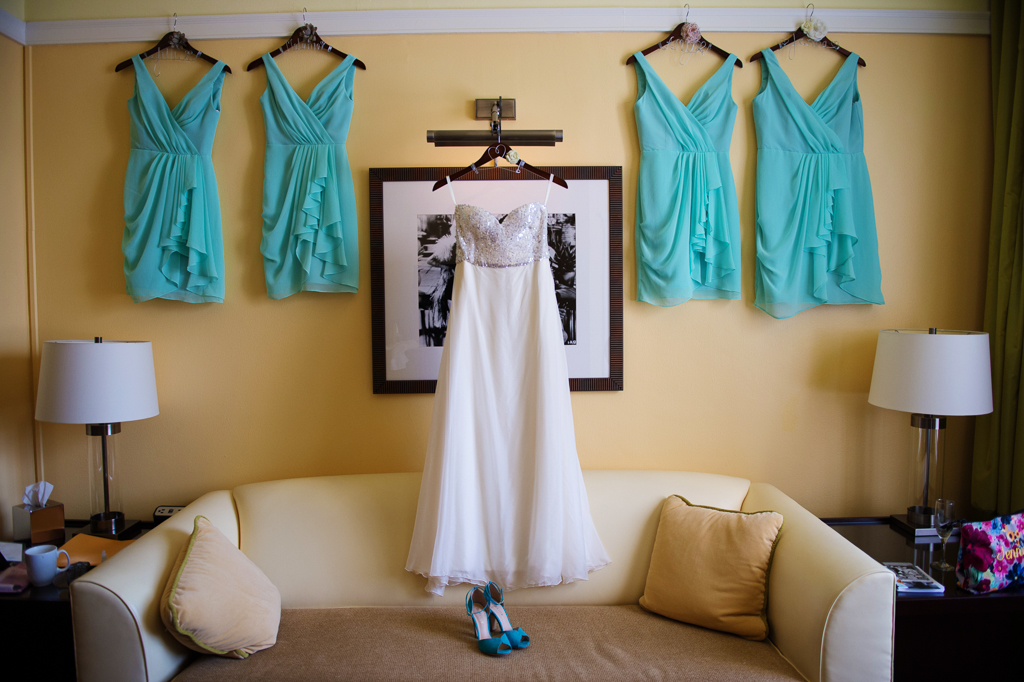 wedding dress and seafoam green bridesmaids dresses hang on the wall of hotel deluxe