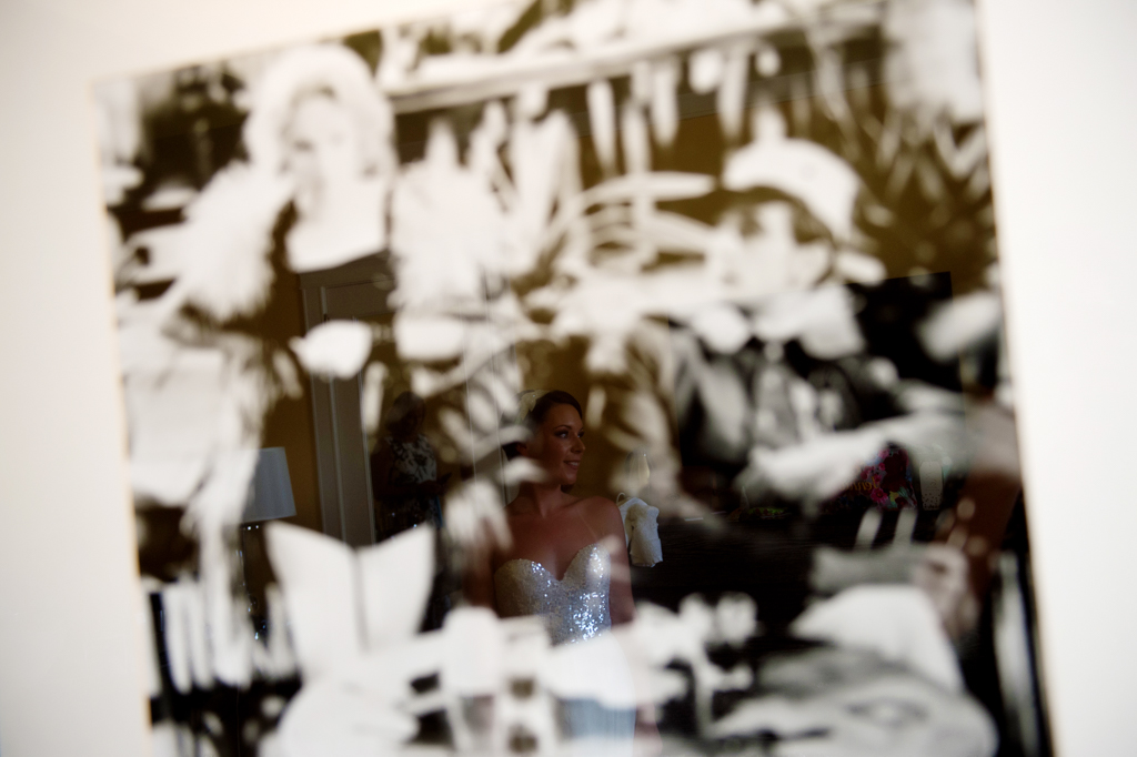 a bride is seen in the reflection of a framed vintage hollywood photograph hanging on the wall