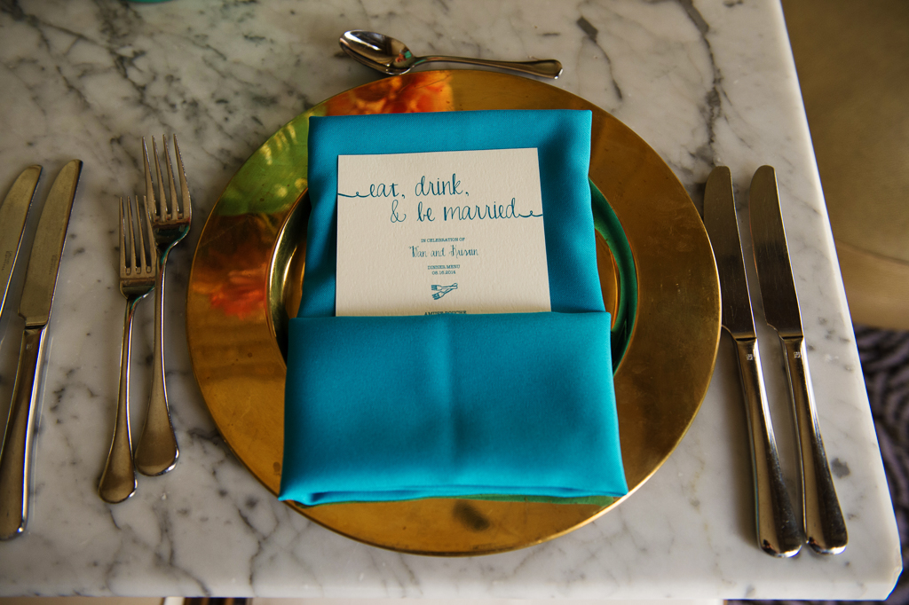 gold plates and turquoise napkins hold wedding reception dinner menu