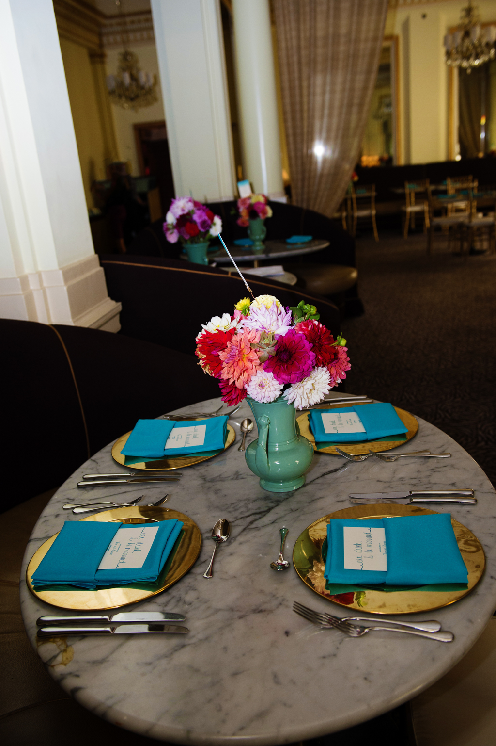 vintage teal vases hold yellow red and orange flowers at wedding reception at Gracies