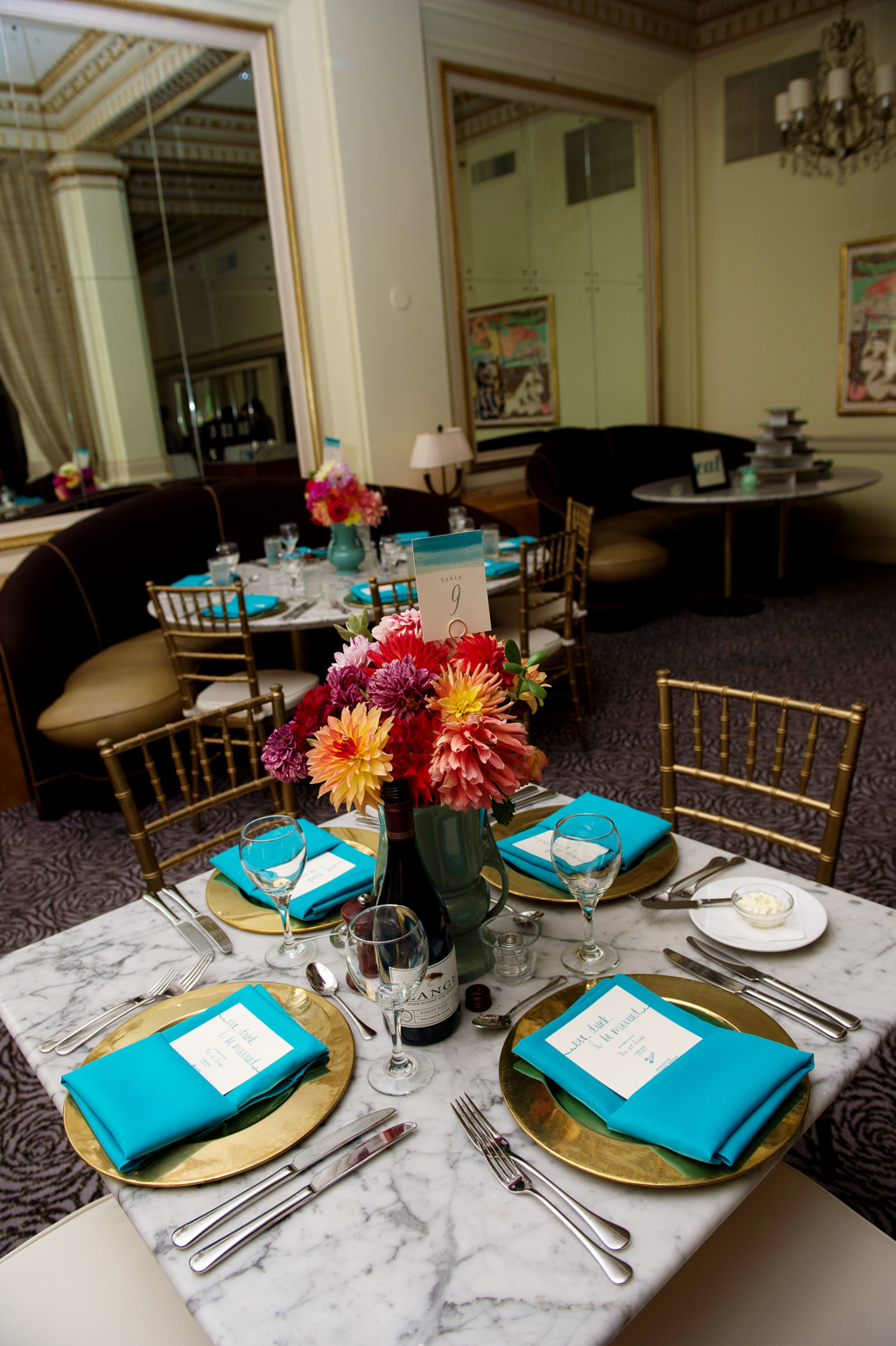 vintage teal vases hold yellow red and orange flowers at wedding reception at Gracies