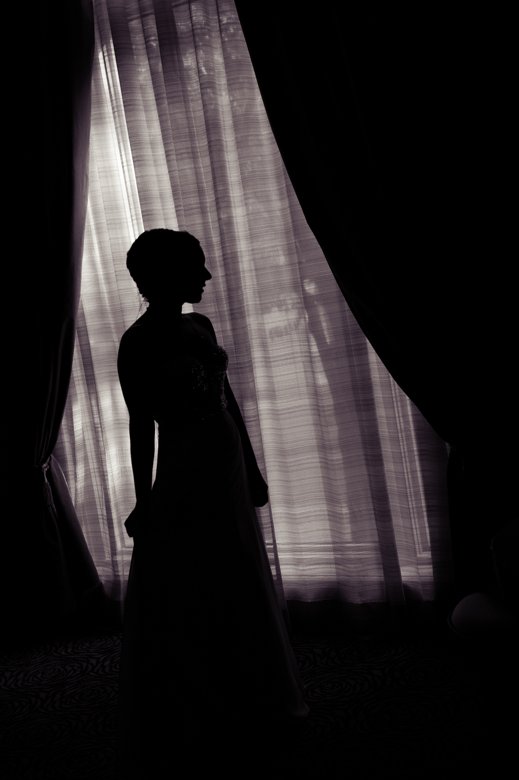 silhouette of bride in front of a window at wedding reception
