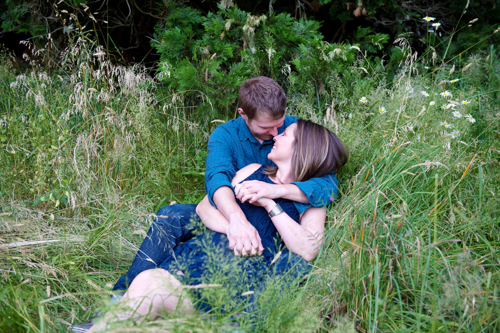 a couple embrace and lay in the tall grass at hoyt arboretum