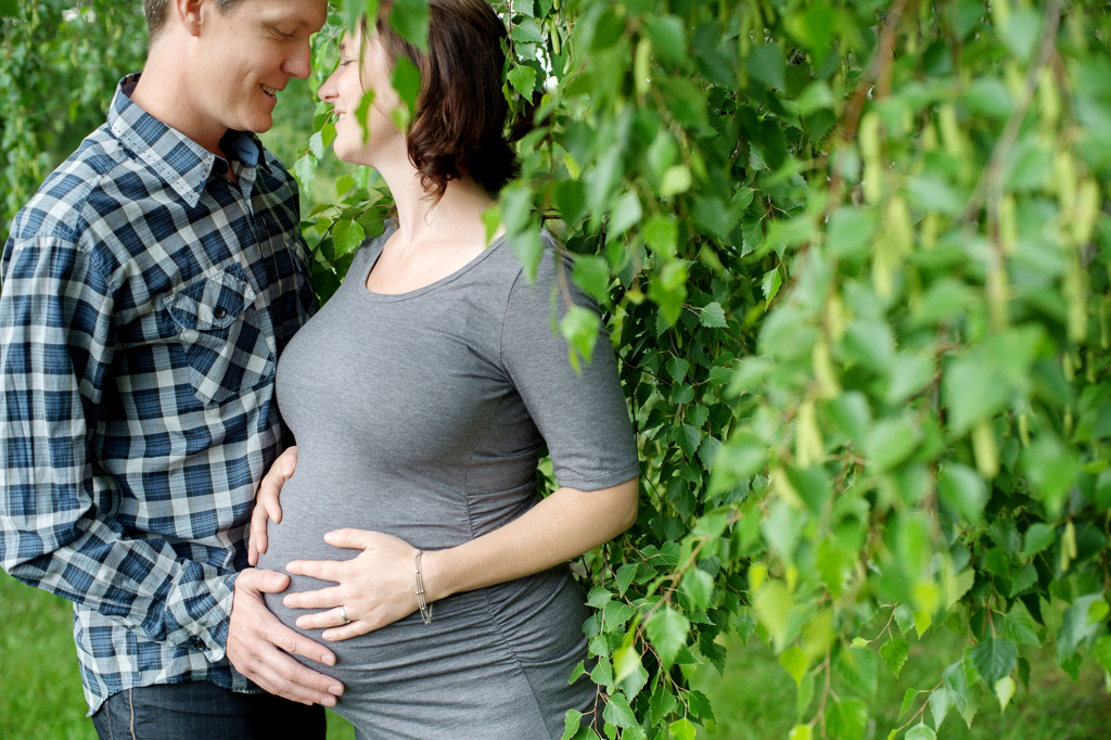 a man feels a woman's pregnant belly at hoyt arboretum