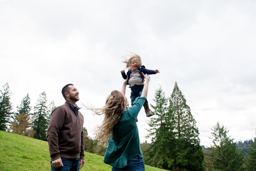 mom tosses daughter into the air as dad looks on