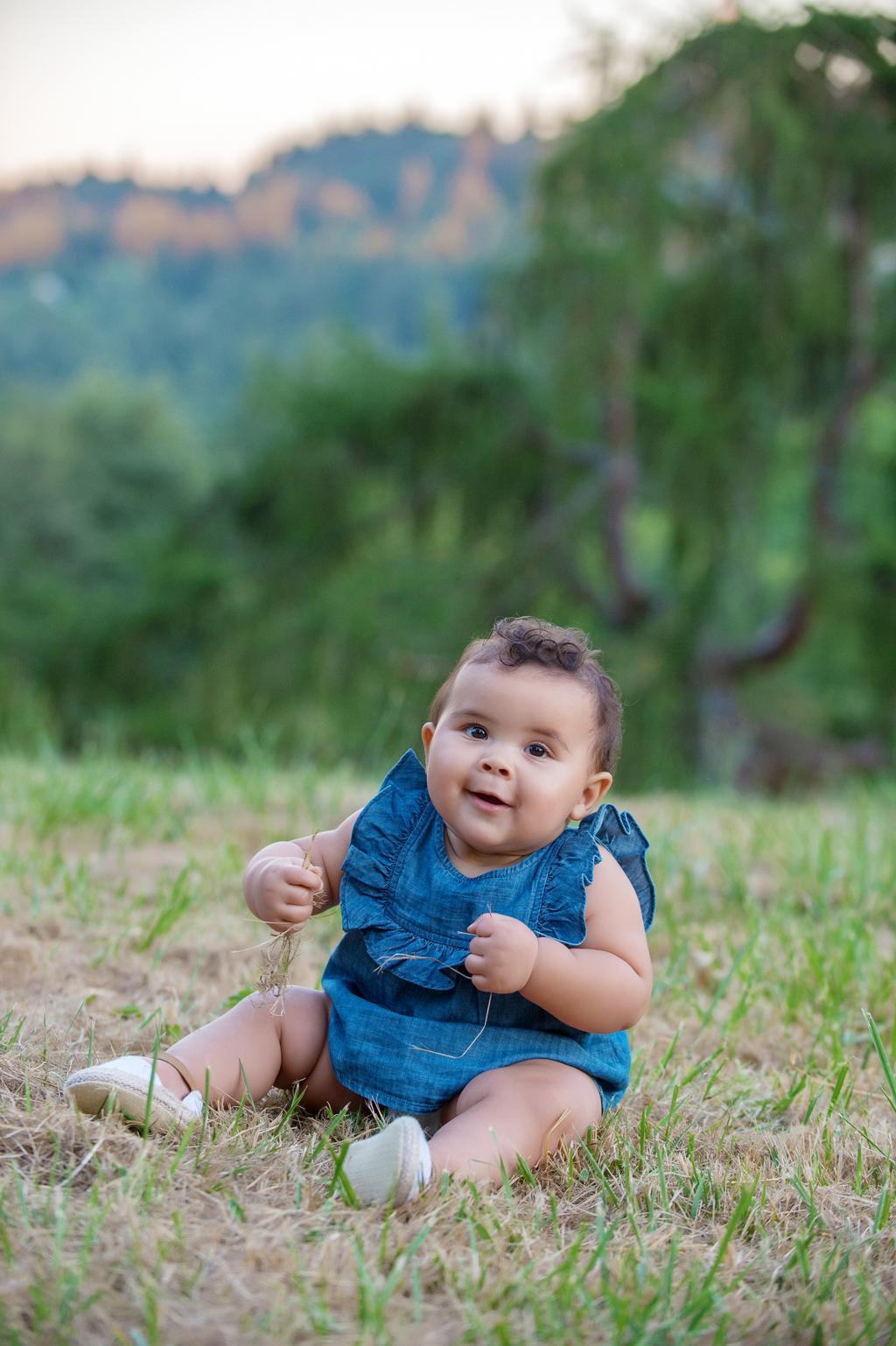 a baby girl sits in the grass at hoyt arboretum