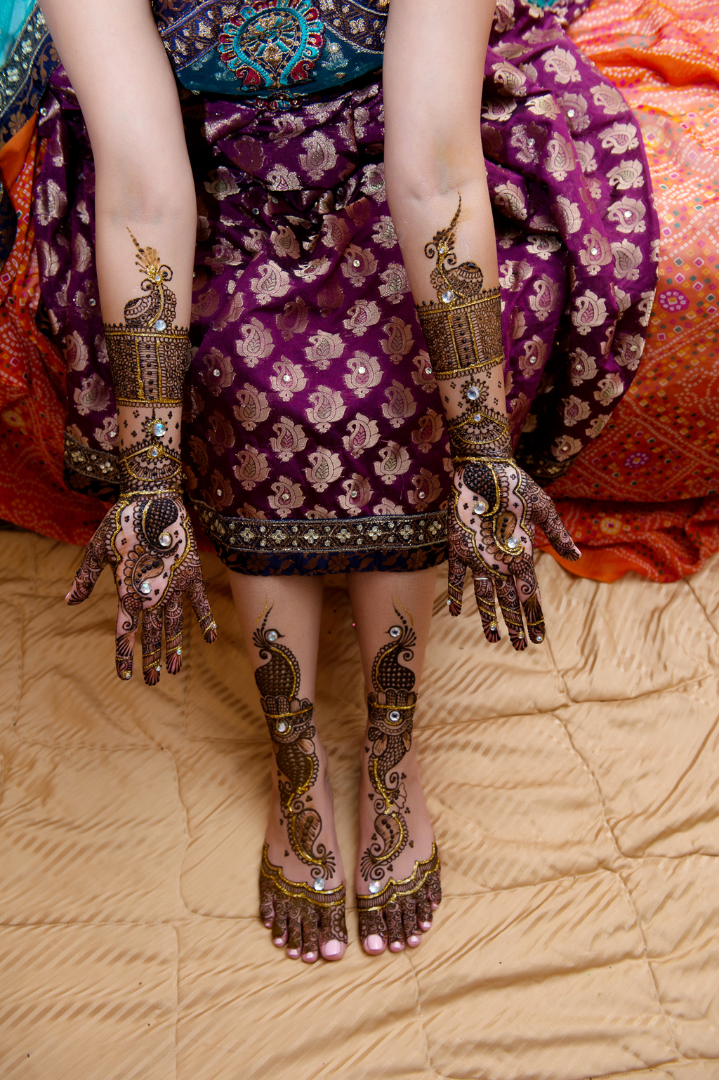 an indian bride shows her hands and feet that were just decorated in mehndi 