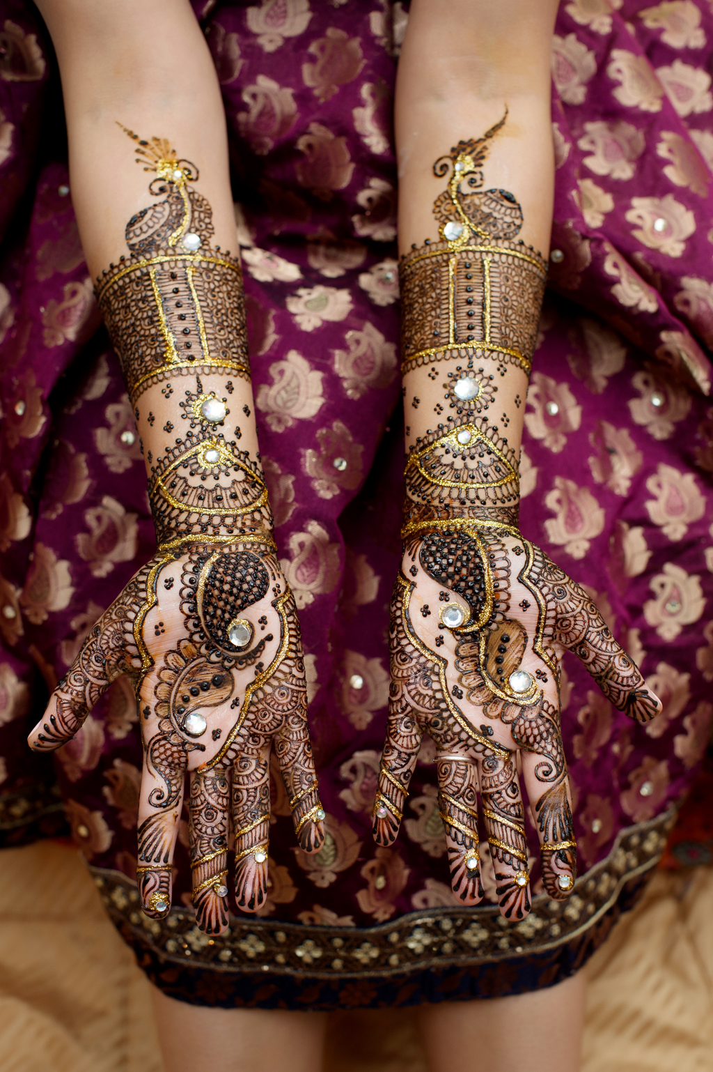 an indian bride holds out her hands that were just decorated in mehndi