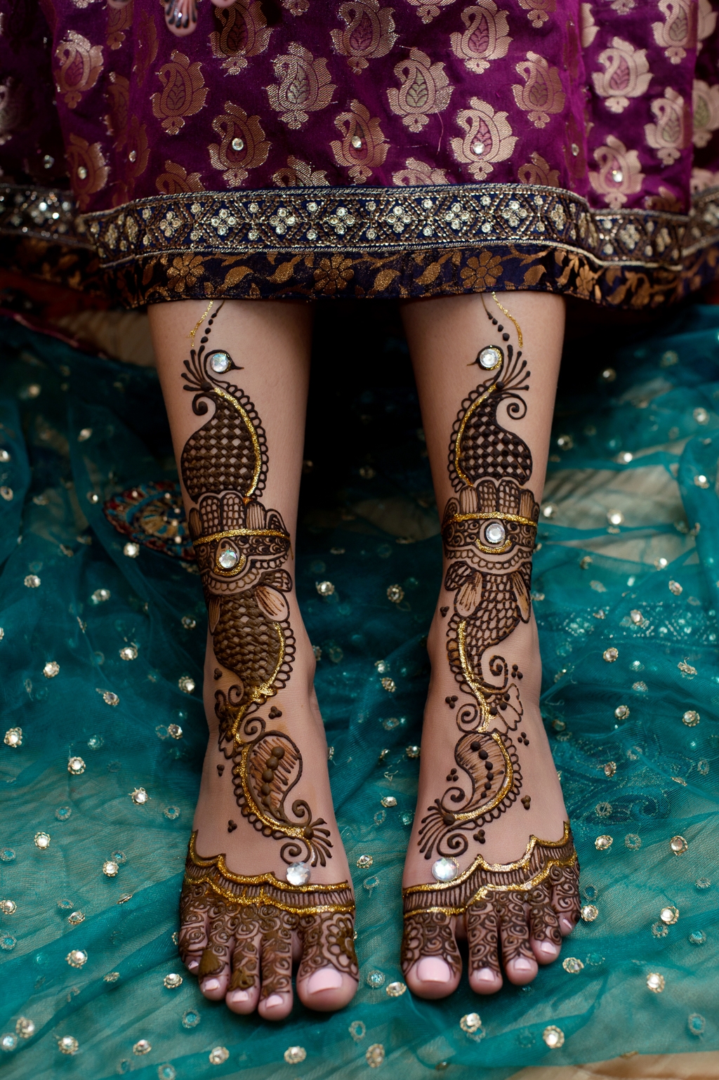 an indian bride shows her feet that were just decorated in mehndi 