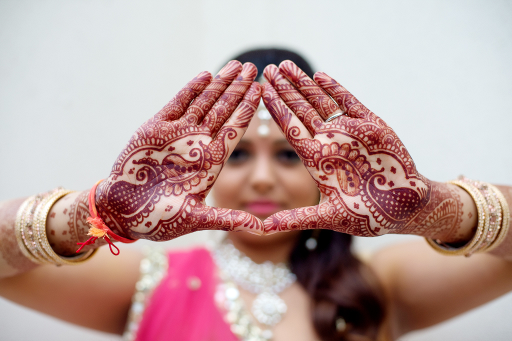 indian bride shows her hands covered in henna 