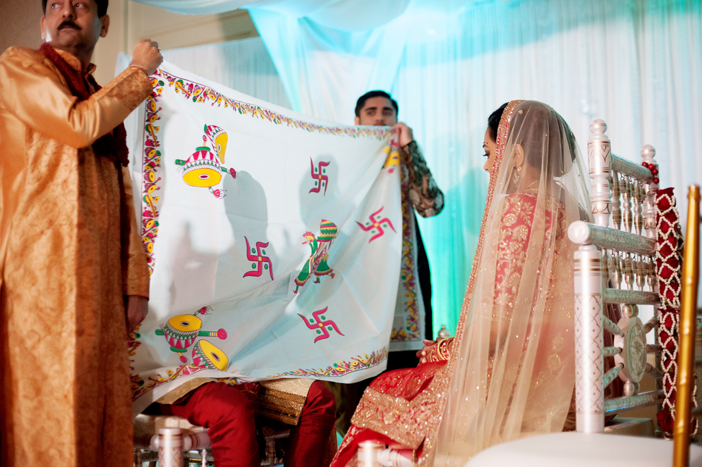 a curtain is held between the bride and groom during an indian wedding