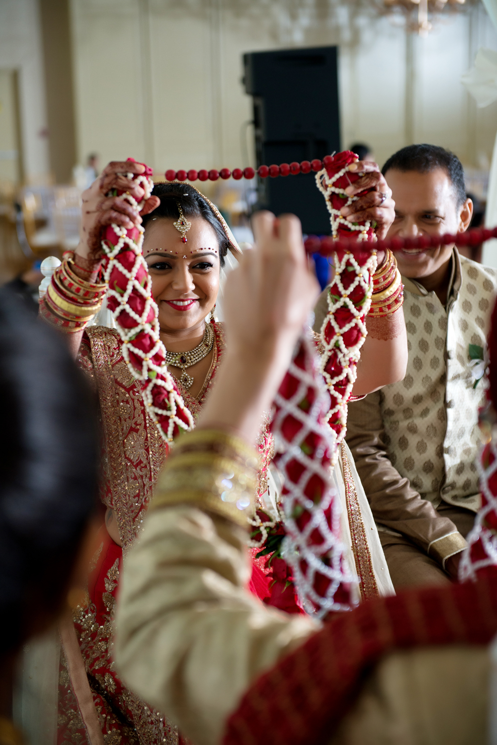 bride and groom exchange red garlands during their indian wedding ceremony
