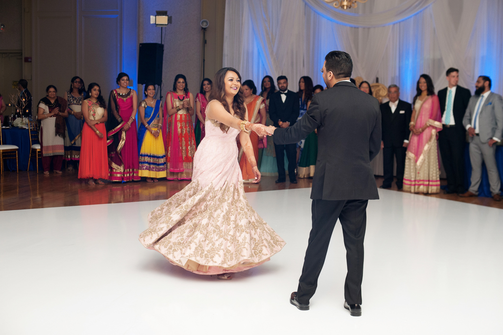 an indian bride wears a pink and gold dress during the couple's first dance