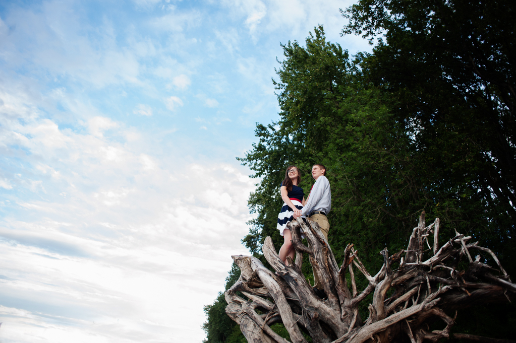 a couple stand on a tall fallen tree stump