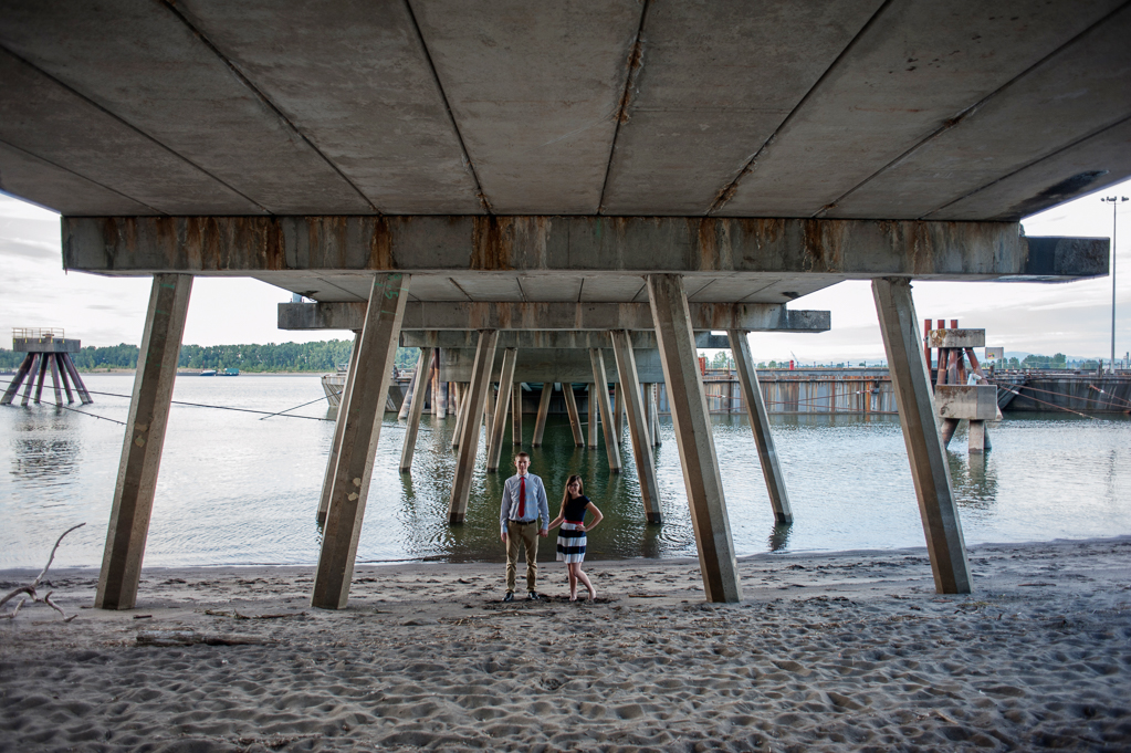 a couple wearing red white and blue stand under a dock at kelley point park