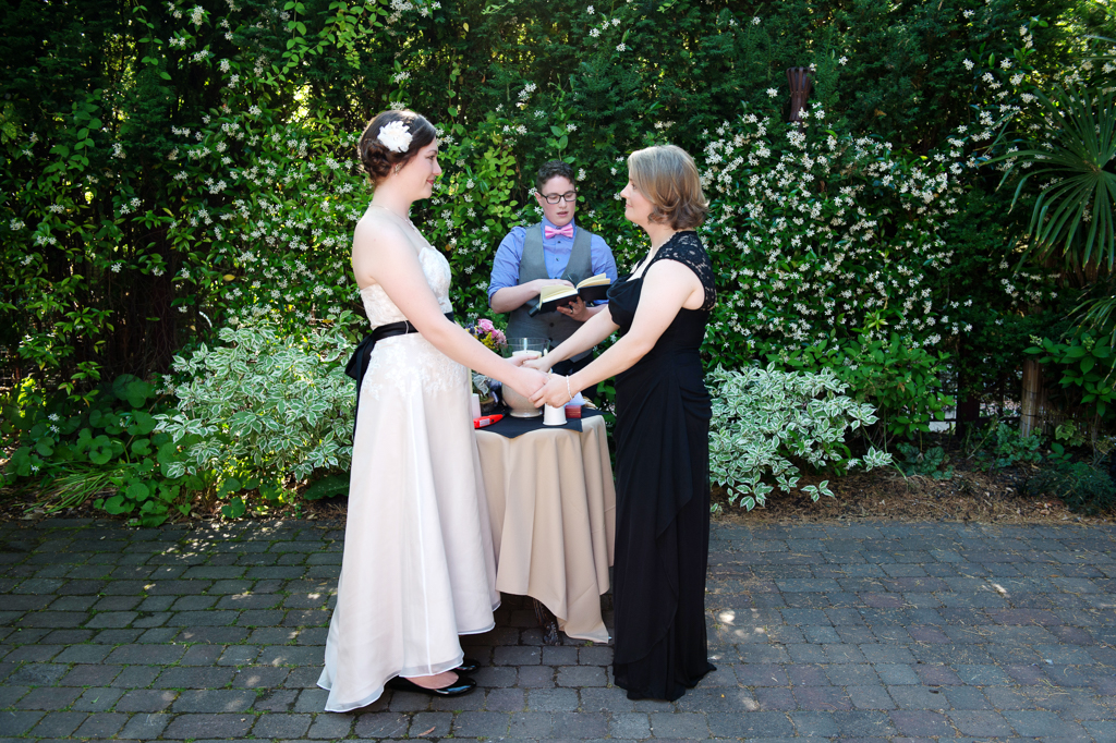 two brides hold hands during their wedding ceremony at kennedy school