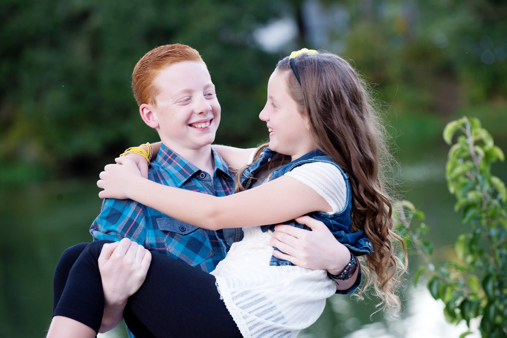 a brother with red hair picks up his sister in his arms