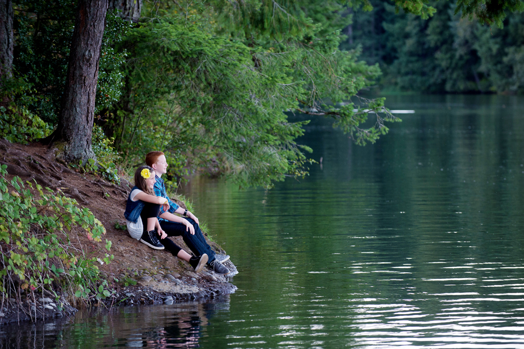 a brother and sister sit on the bank of lakamas lake and look at the water