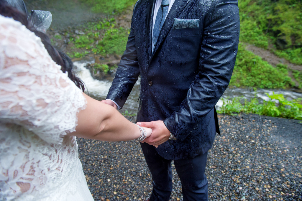 a bride and groom hold hands during their wedding ceremony in the rain
