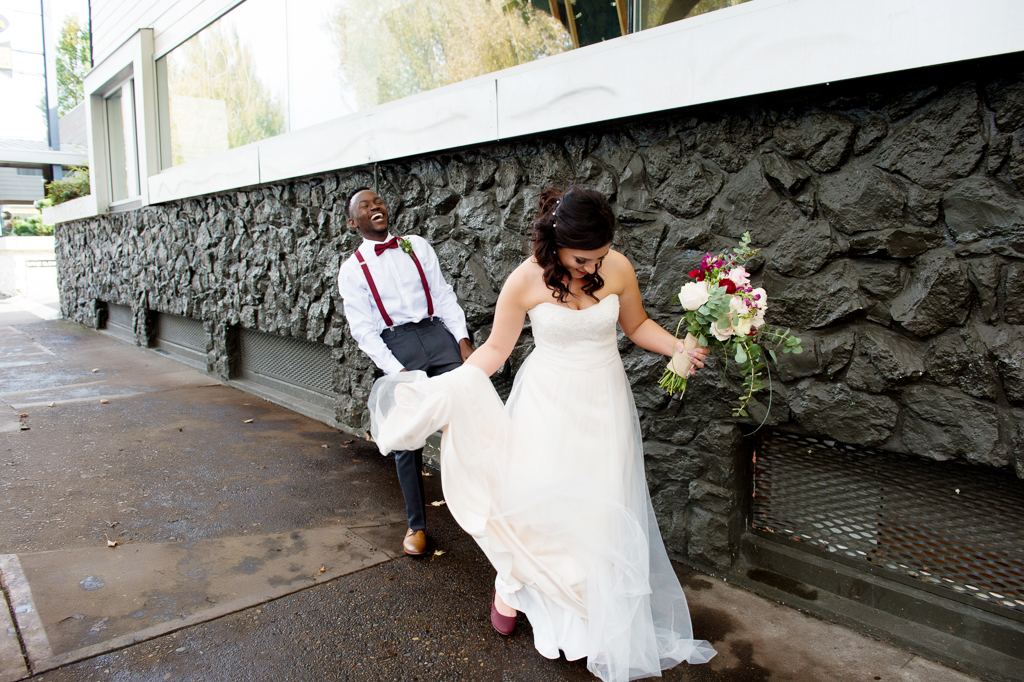 groom laughs as he holds the bride's wedding dress outside of jupiter hotel